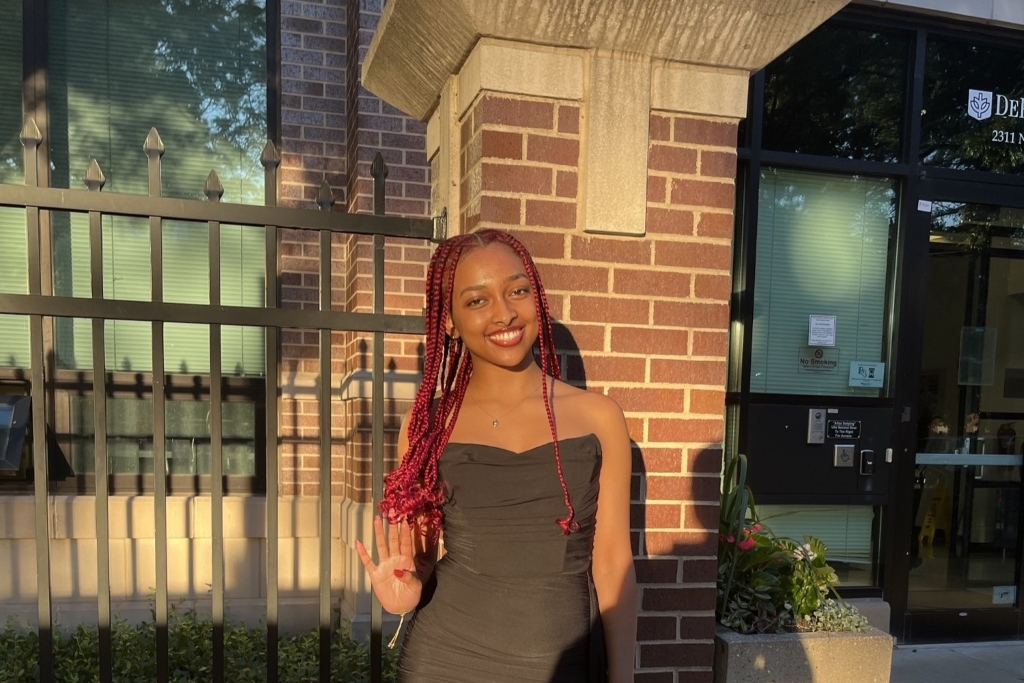 a young woman poses in front of a brick academic building